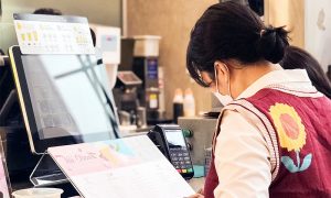 Thu ngân xuất hóa đơn điện tử từ máy tính tiền cho khách hàng tại cửa hàng bán lẻ